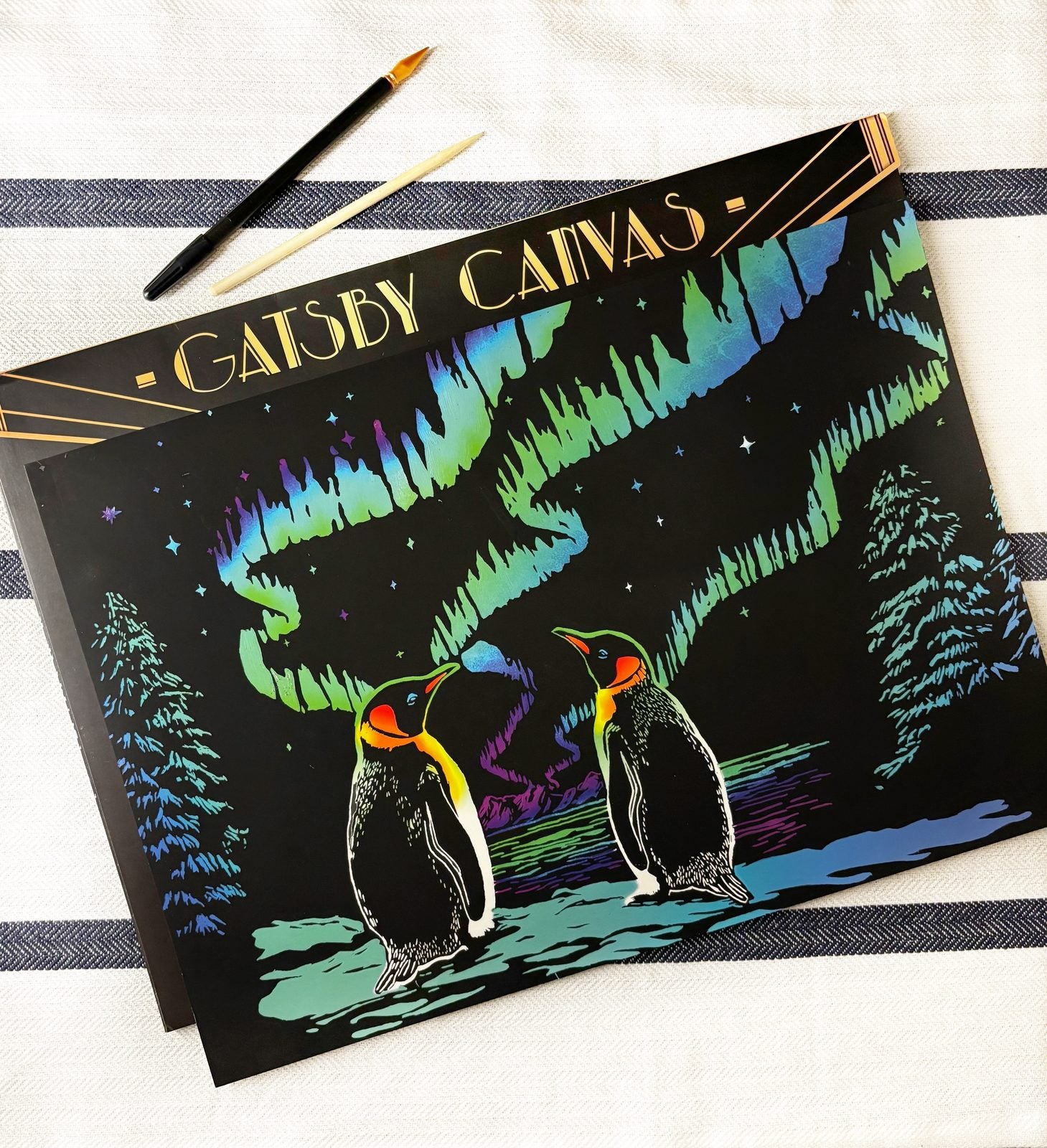 A finished penguins scratch-art canvas displayed in a lifestyle setting